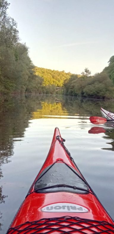 Die Spitze eines roten Kajaks auf der Lahn und stehendes Gewässer.